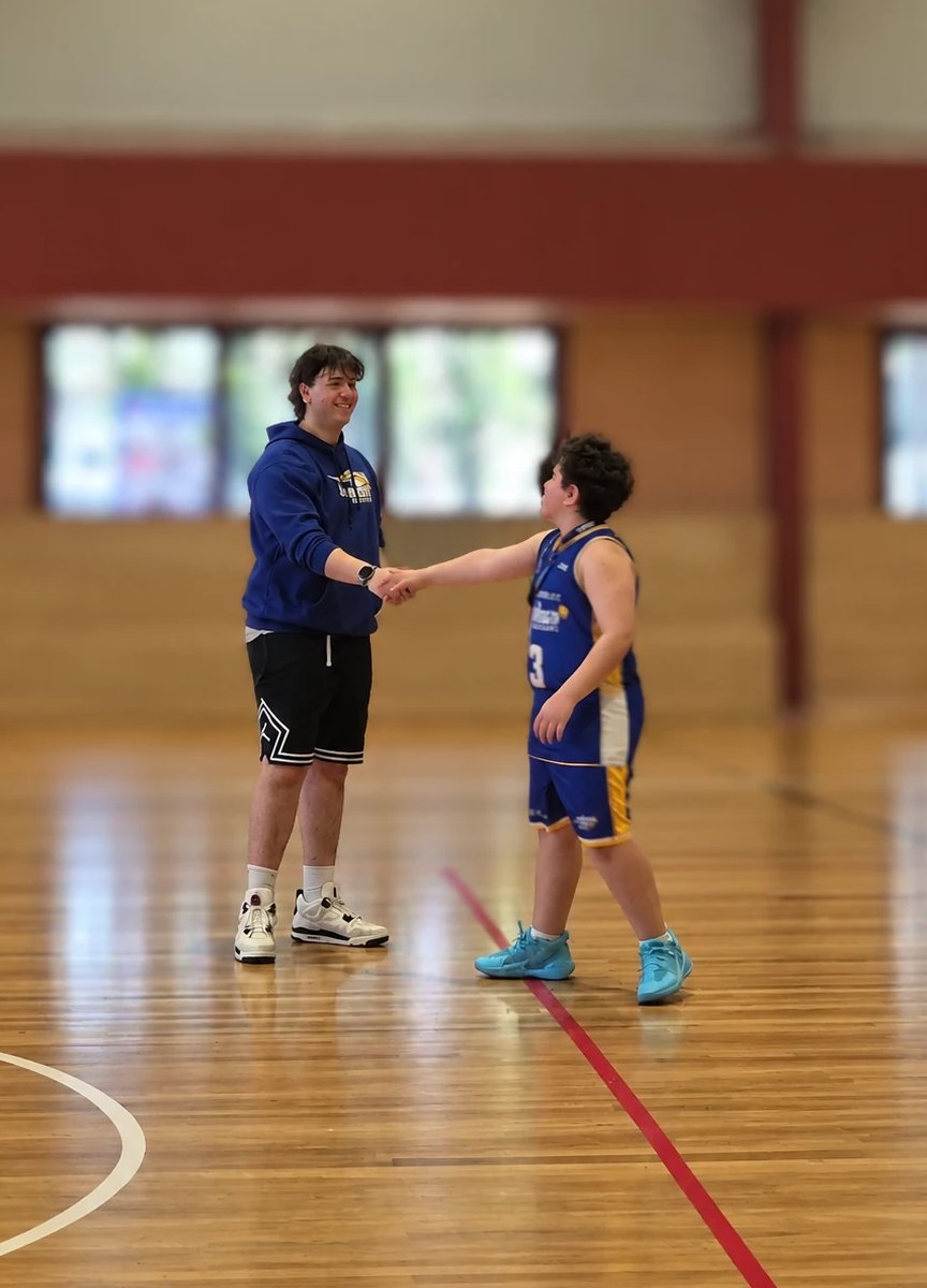 Coach Isaac shaking hands with a young player on the court